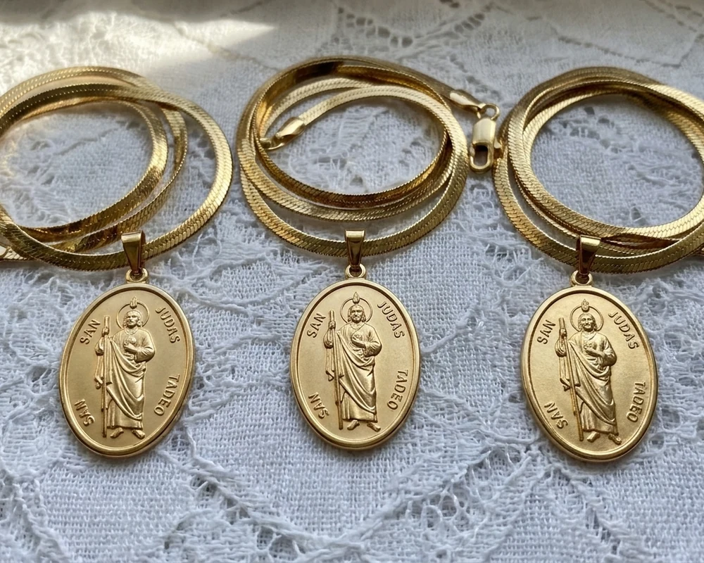 Three gold St. Jude™ Hope Pendants on a lace tablecloth